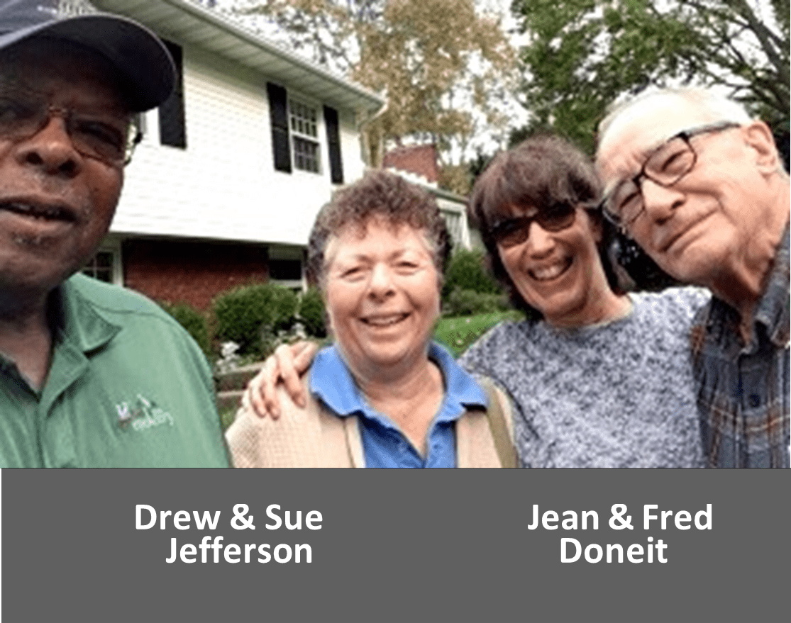 Four smiling adults posing for a group photo outdoors.