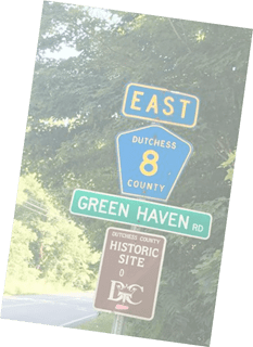 Directional road signs indicating east dutchess county route 8 and green haven road next to a historic site marker.