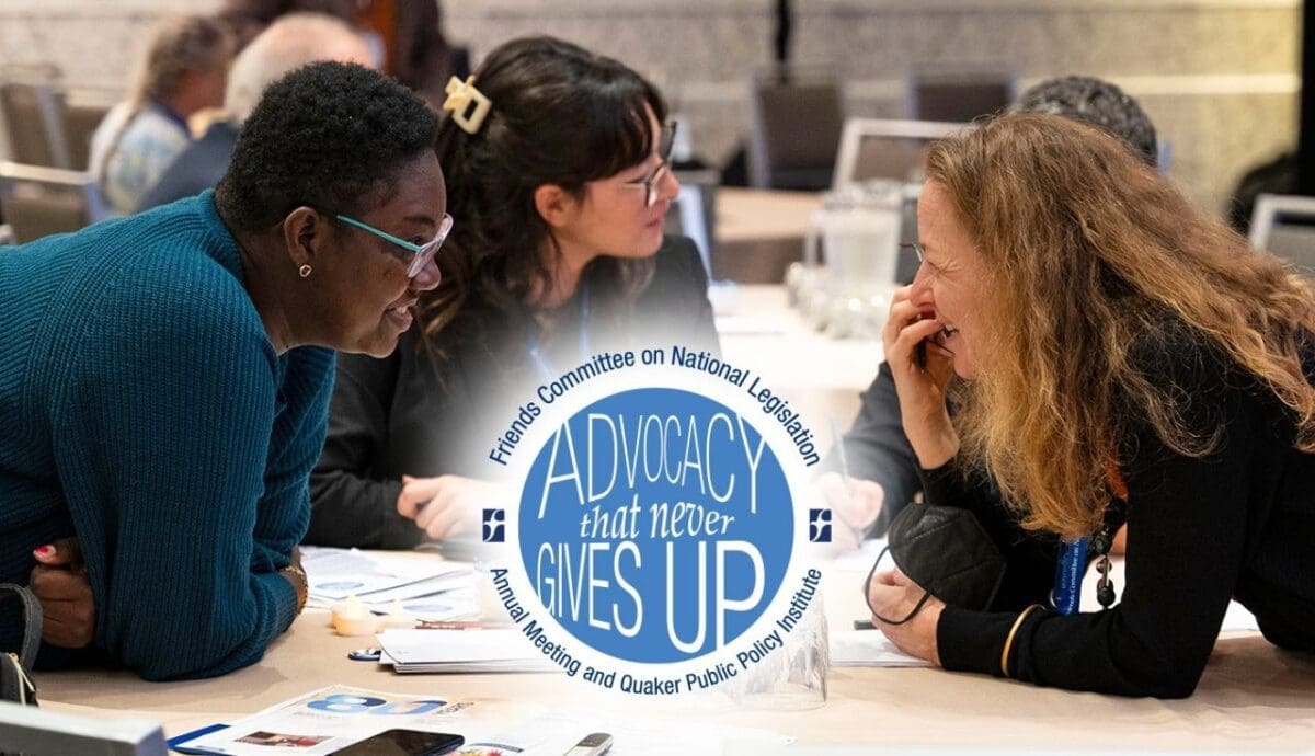 People are engaging in discussion around a table at the Friends Committee on National Legislation's Annual Meeting and Quaker Public Policy Institute. A sign reads "Advocacy that never gives up.